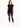 A woman stands wearing a black short-sleeve top with a heart design, paired with distressed blue jeans and white snea...