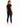 A woman stands with her back to the camera, wearing a black shirt and dark skinny jeans, paired with white sneakers.