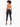 A woman with curly hair poses from the back, wearing a halter top and fitted black jeans with high heels.
