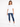 A woman stands wearing a loose-fitting white tee and distressed blue jeans, paired with white sneakers.