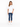 A woman stands in a relaxed pose wearing a white oversized tee and distressed blue jeans with white sneakers.