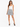 A woman stands confidently in a playful, patterned skirt paired with a fitted white tank top and stylish black heels.
