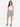 A woman stands confidently in a flared skirt with a black and white spotted pattern, paired with a fitted top and heels.