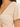Close-up of a light beige top featuring a deep V-neck and gathered detailing at the front.