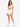 A model wearing a beige cropped top with a drawstring detail, paired with white shorts and white sneakers.