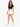 A woman stands confidently in a black cropped top and white shorts, paired with white sneakers.