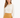 A woman wearing a cream blouse with a chain neckline, paired with a mustard-colored skirt.
