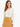 A woman wearing a cream blouse with a chain neckline, paired with a mustard-colored skirt.
