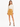 A model wearing a long-sleeve cream top paired with a mustard-colored mini skirt and black strappy heels.