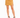 A model wearing a mustard-colored mini skirt with a side slit, paired with black strappy high heels.