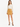 A woman stands confidently in a light blouse with a chain detail and a mustard-colored mini skirt, paired with black...