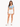A woman stands confidently in a light blue cropped top and white high-waisted shorts, paired with white sneakers.