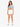 A woman stands confidently in a light blue cropped top and white shorts, paired with white sneakers.