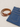 A brown leather belt with a silver buckle placed beside folded blue denim jeans on a light fabric background.