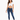 A woman stands confidently in a cropped white top and fitted blue jeans, paired with white sneakers.