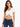 A woman models a white cropped top with a ruched front, paired with dark blue jeans.