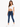 A woman poses in a fitted white crop top and blue skinny jeans, paired with white sneakers.