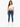 A woman stands confidently in a white cropped top and fitted blue jeans, paired with white sneakers.