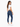 A woman with long, wavy hair wears a fitted white crop top and dark blue skinny jeans, posing from the back.