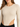 Close-up of a model wearing a ribbed long-sleeve bodysuit with a side cutout in a neutral beige color.