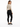 A woman in a fitted, long-sleeve bodysuit with a cutout back, paired with black skinny jeans and sneakers.