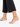 A close-up of a bare foot adorned with a delicate anklet featuring black beads and a gold peace symbol.