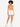 Model wearing an orange bodysuit with a cutout, paired with white shorts and white sneakers.