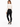 A model wearing a fitted long-sleeve bodysuit with an open back, paired with black skinny jeans and sneakers.