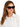 A woman with long hair wears stylish black sunglasses with a tortoiseshell pattern, paired with a light shirt.