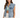 A woman wearing a light blue denim vest over a green top, styled with casual white pants.