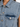 Close-up of a light blue denim vest featuring a pointed collar and a chest pocket with a silver snap button.