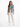 A woman stands confidently in a sleeveless denim vest paired with a light green top and beige trousers.