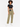 A model stands wearing olive green pants with a black belt, paired with a cropped black top and white sneakers.