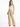 A model wears high-waisted, wide-leg beige pants paired with a delicate white camisole and stylish black heels.