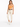 A woman stands confidently in light-colored pants, paired with a fitted orange top and white sneakers.