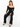 A woman sits on a white cube, wearing fitted black pants and a stylish off-the-shoulder top with long sleeves.