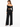 A woman wearing black wide-leg pants and a cropped off-the-shoulder top, viewed from the back.