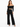 A model poses in black high-waisted pants paired with a cropped off-the-shoulder top and strappy heels.