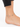 Ankle adorned with a delicate gold chain featuring blue eye-shaped beads, resting on a bare foot.