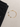 A delicate gold anklet featuring colorful beads and circular charms, displayed beside black denim.