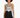A model with curly hair wears a patterned bodysuit paired with high-waisted black denim shorts.