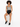 A model with curly hair sits on a white cube, wearing a patterned bodysuit and black high-waisted shorts.