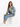 A woman sits on a white cube wearing a light blue denim jacket, green crop top, and matching jeans with white sneakers.