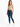 A woman stands confidently in a light green cropped top and dark blue skinny jeans, paired with white sneakers.