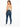 A woman with long hair wears a light green cropped top and high-waisted blue jeans, standing in profile.