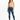 A model wearing a light green cropped top with spaghetti straps paired with distressed blue jeans and white sneakers.