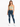 A model wearing a light green cropped top with spaghetti straps paired with distressed blue jeans and white sneakers.