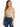 A woman wearing a light green cropped top with thin straps paired with distressed blue jeans.