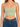 Light green cropped top with thin straps, paired with high-waisted blue denim jeans.