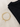 A gold bracelet featuring a crescent moon and star charms, placed beside a folded black shirt on a light background.